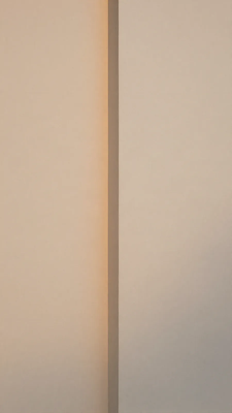 A narrow shaft of afternoon light on a warm plaster wall.